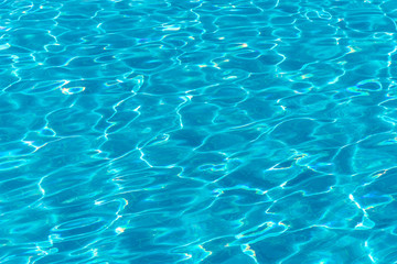 Blue bottom through the transparent water with sunspots of light in the pool