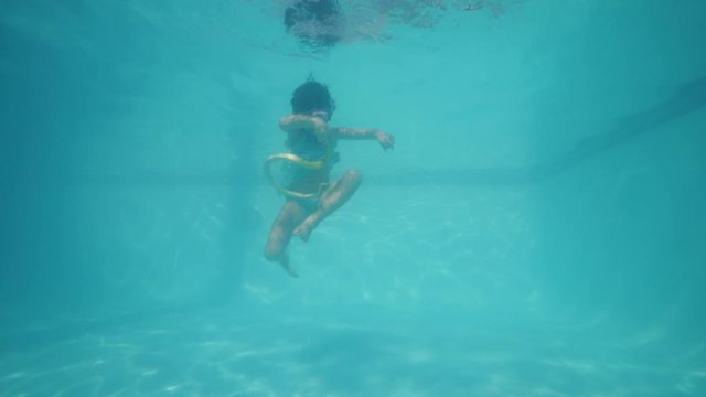 A little girl swimming and playing a snake toy underwater.
