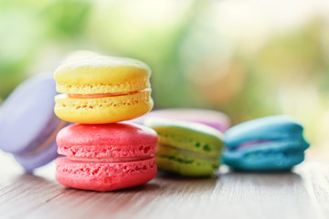 colorful french macarons on wooden table over nature background 