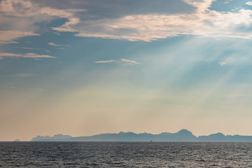 Dramatic sun rays hitting the sea off the coast of Thailand. Hills of Phi Phi Island can be seen in the background.