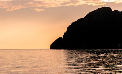 Dramatic Silhouette of mountains and boats in the middle of andaman sea near Phi Phi Islands during sunset.