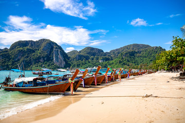 traditional wooden longtail boats parked at a beach in Phi Phi Island. Clear water and clean beach.