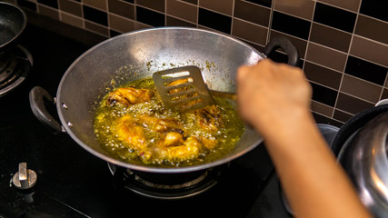 Close up view of a raw chicken meat fried in a wok with hot boiling oil at the kitchen.