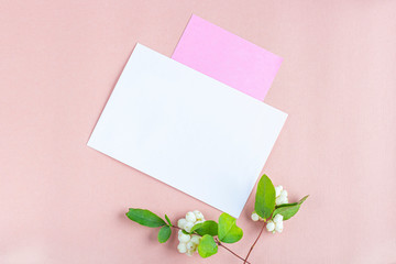 Invitation card mockup. Template blank greeting card to the wedding, birthday and other events. Paper on peach color background with white flowers. Concept of writing romantic  for Valentines day