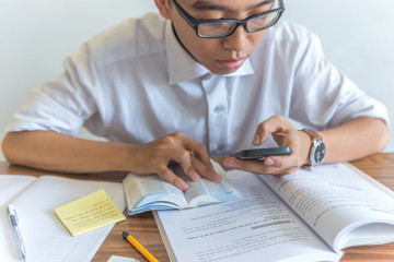 Young student using smartphone and doing homework