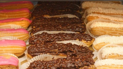Chocolate, Strawberry And Vanilla Glazed Eclairs On Display. Closeup.