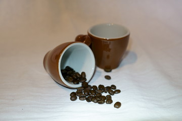two brown coffee cups with coffee beans over white background