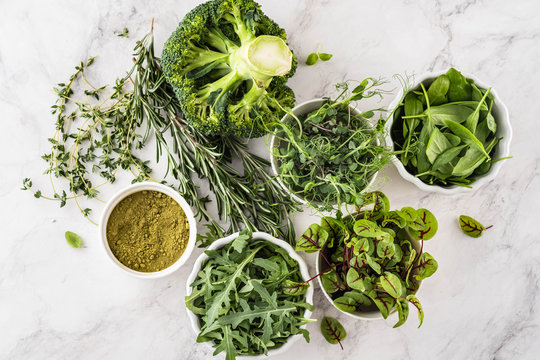 Fresh Green Vegetables Variety On White Background From Overhead, Broccoli, Thyme, Rosemary, Spinach, Microgreens.