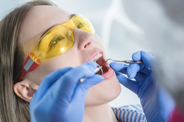 A dentist examines a patient, close-up of a patient with an open mouth next to which dental objects