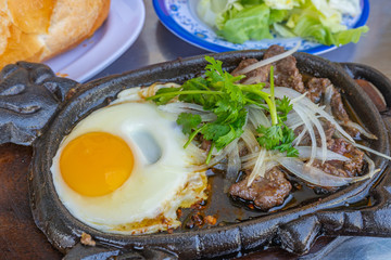 Delicious sizzling beef fillet and sunny egg on iron platter