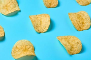 Rows of fried potato chips on blue background. Close-up