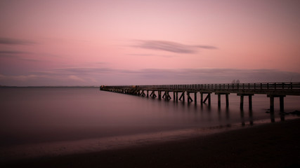 Long exposure image of people fishing on Cornwallis Wharf in Auckland at sunset