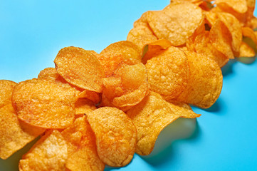 Row of spicy fried potato chips on blue background. Close-up