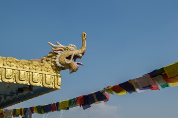 A dragon in the corner of a roof and praying flags in a temple in Bouddhanath Stupa in Kathmandu,...
