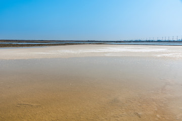 Background of sea water prepare in the salt field to let it dry from sun with blue sky in Thailand,...