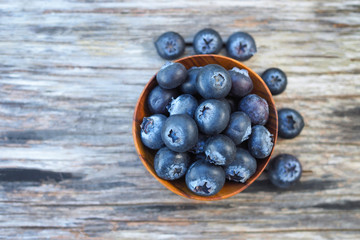 Blueberries in wooden bowl on wooden background