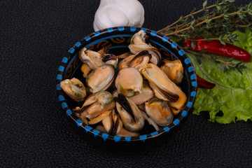 Pickled mussels in the bowl served pepper, garlic and salad