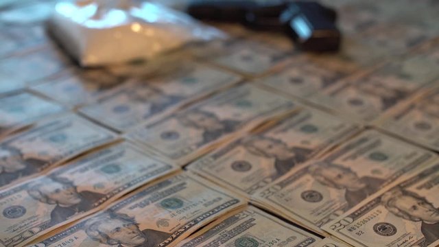 Rack focus shot from rows of $20 USD to drugs and gun.