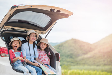happy woman girl goes to summer travel trip in the car with mountain background. Family and...