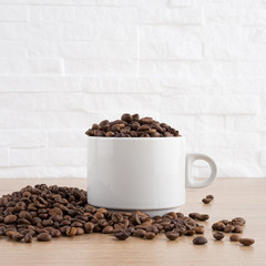 cup of coffee with coffee seeds on wooden table and light brick background