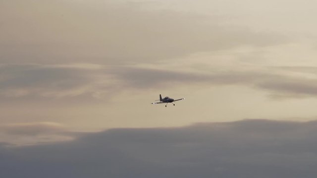 A small homebuilt airplane turns toward the camera near sunset at a small airport.