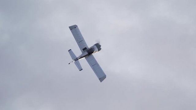 A small homebuilt airplane turns over a small airport in slow motion.