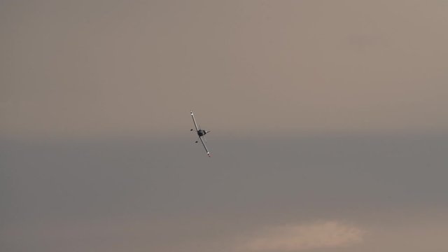 A small homebuilt airplane turning and approaching head-on at a small airport near sunset.