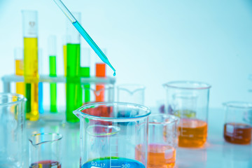 Several test tubes and solution beakers in a science laboratory with liquid of different colors on the laboratory table for chemical background