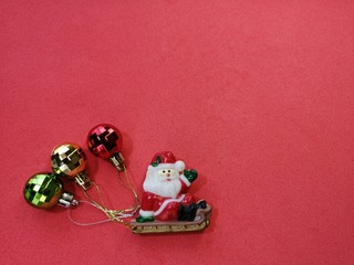 santa claus greets merry christmas with colored balls on the back on a red background below