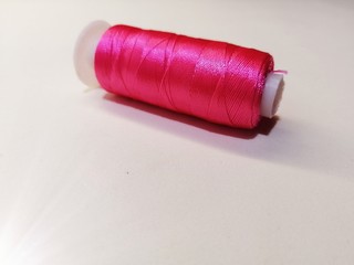 spool of new silk pink thread on a white background