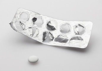 Empty, used, opened blister with last one white pill on white background - healthcare and...