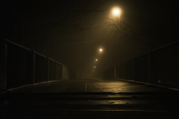 empty bridge with lights in dark foggy night