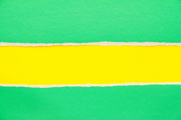 Green torn sheet of cardboard on yellow paper background. Can be used for text.