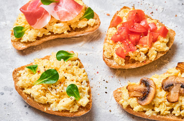 Scramble omelet sandwiches, bacon, mushrooms, tomatoes and fresh herbs on a light gray background.