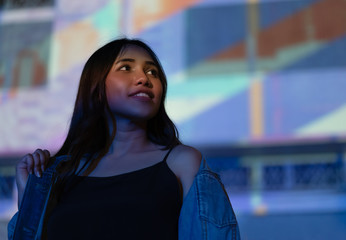 Young woman standing outdoors at night with light glare