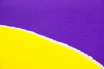 Yellow torn piece of cardboard on purple sheet of paper texture background. Can be used for text.