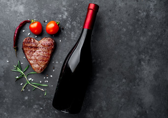 grilled beef steak in the form of a heart with spices and a bottle of wine for dinner for...