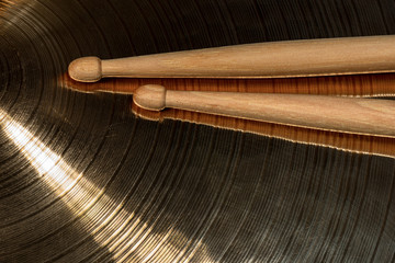 Close-up of a pair of wooden drumsticks on a metal cymbal. Percussion instrument