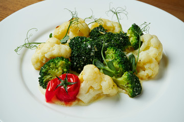 Close up view on Steamed cauliflower and broccoli with cream sauce on a white plate. Healthy, dietary food. Food with vitamins. Vegetarian