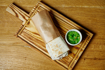 Top view Fresh roll in pita bread with chicken kebab, sauce and vegetables on a wooden board. Street food. Shaurma or shawerma