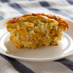 Delicious Homemade Cheddar Corn Pudding Casserole on a white plate, side view. Close-up.