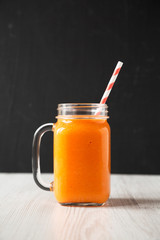 Homemade Mango Carrot Smoothie in a glass jar mug, side view. Close-up.
