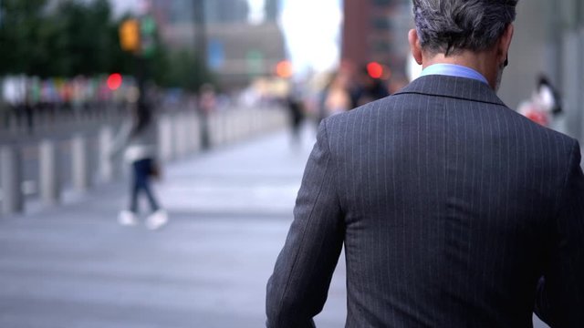 Slow motion effect of male executive manager in corporate suit using mobile phone outdoors in city, businessman in elegant formal suit sending text messages via smartphone connected to 4G internet 