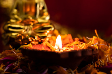 front close up shot a glowing lamp with buddha statue blurred in the background. meditation and peace concept.