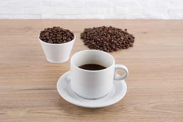 cup of coffee with coffee beans on wooden table and white wall