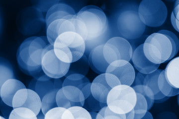 Shimmering abstract circles defocused christmas lights background toned trendy classic blue color of year 2020. Out of focus holiday background christmas tree. Light bokeh from Xmas tree. 