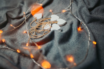 Saint Valentine's day card. White wooden hearts on the gray background. Hearts with garland light.
