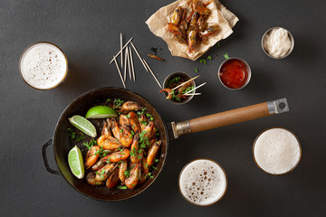 Fresh craft beer in glasses and a shrimp appetizer with herbs and sauces. Black concrete, top view