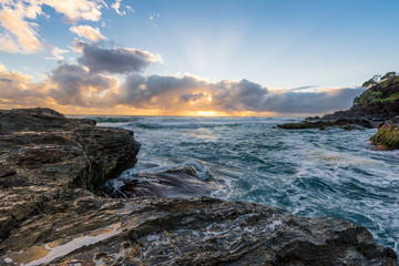 sunrise with waves crashing over the rocks 