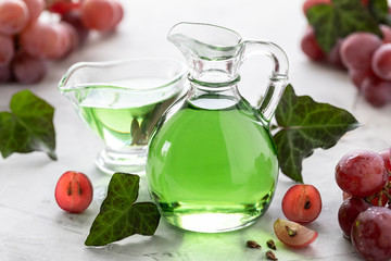 Grape seed oil in a glass bottle with a bunch of grapes on a white background.